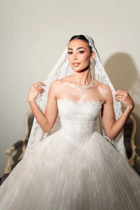 Bride lifting her veil in a full tulle gown — classic luxury bridal makeup