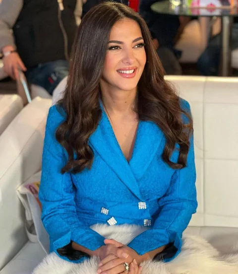 Television press appearance in a sky-blue suit — polished daytime celebrity makeup